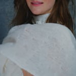 A woman wears a 100% silk pussybow sleeveless blouse in white with a matching cashmere lace shawl