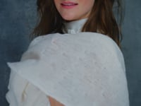 A woman wears a 100% silk pussybow sleeveless blouse in white with a matching cashmere lace shawl