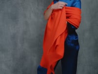 A lady wears a 100% cashmere wrap shawl in orange with a pure silk 3/4 sleeve blouse in teal with matching trousers