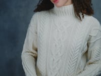 A woman wears a traditional Irish Aran Sweater made in 100% Cashmere and black silk skirt