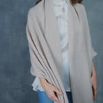 A woman wears a large cashmere shawl in beige over a white silk pussybow top