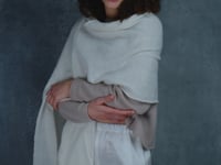 A woman wears a cropped cashmere sweater in beige with white silk shorts and matching white cashmere wrap