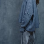 A woman wears a pure cashmere sweater that is oversized in grey with a silver skirt