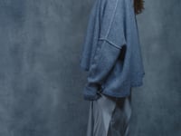 A woman wears a pure cashmere sweater that is oversized in grey with a silver skirt