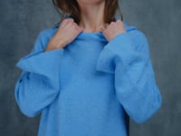 A woman wears a pure 100% cashmere hoodie sweater in blue with black silk shorts