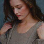 A woman wears a pure cashmere twinset cardigan with matching vest top in Beige with silk shorts in black