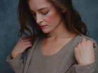 A woman wears a pure cashmere twinset cardigan with matching vest top in Beige with silk shorts in black