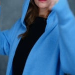 lady standing with 100% cashmere tee short sleeve sweater in black with blue cashmere coat over top