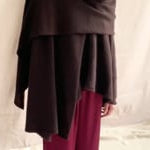 video of a woman wearing a large cashmere wrap shawl in dark brown eith matching cashmere beanie hat and burgundy silk trousers