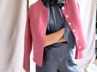 video of a woman wearing a cashmere cardigan  in dusty pink rose with mother of pearl buttons over dark grey silk top and trousers