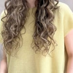 a video of a woman wears a cashmere tee in butter yellow over silk trousers in chocolate brown 