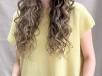 a video of a woman wears a cashmere tee in butter yellow over silk trousers in chocolate brown 