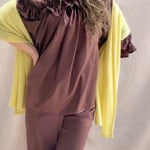 a video of a woman wearing a banana yellow cashmere wrap shawl over a ruffled silk blouse top in chocolate brown with matching trousers 