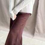 a video of a woman wearing a hand knit Irish 100% Cashmere Aran Sweater with Turtleneck in cream beige colour over chocolate brown silk trousers