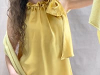 a video of a woman wearing a large cashmere scarf in pale yellow with matching cashmere beanie hat and cashmere tee sweater by Madigan Cashmere 