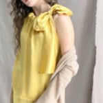 a video of a woman wearing a long cashmere cardigan coat in sand beige colour over silk top and trousers in butter yellow by Irish brand Madigan