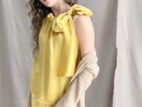 a video of a woman wearing a long cashmere cardigan coat in sand beige colour over silk top and trousers in butter yellow by Irish brand Madigan