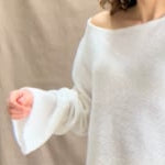 a video of a woman wearing a pure 100% cashmere sweater jumper in white over yellow silk trousers
