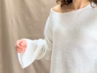 a video of a woman wearing a pure 100% cashmere sweater jumper in white over yellow silk trousers
