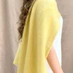 a video of a woman wearing a banana yellow cashmere wrap shawl over a white silk top and yellow silk trousers