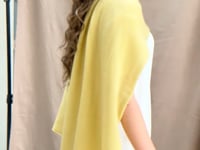 a video of a woman wearing a banana yellow cashmere wrap shawl over a white silk top and yellow silk trousers