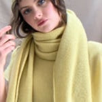 a video of a woman wearing a large cashmere scarf in pale yellow with matching cashmere beanie hat and cashmere tee sweater by Madigan Cashmere 