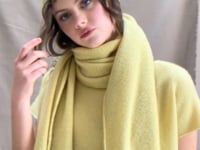 a video of a woman wearing a large cashmere scarf in pale yellow with matching cashmere beanie hat and cashmere tee sweater by Madigan Cashmere 