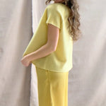 a video of a woman wearing a pure 100% cashmere tee sweater in butter yellow over silk trousers in butter yellow with a mathing cashmere beanie hat in butter yellow