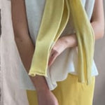 a video of a woman wearing a cashmere scarf in pale yellow over a cashmere tee sweater in white and butter yellow silk skirt by Irish brand Madigan Cashmere