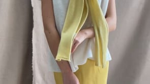 a video of a woman wearing a cashmere scarf in pale yellow over a cashmere tee sweater in white and butter yellow silk skirt by Irish brand Madigan Cashmere