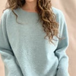video of A woman wears a lightweight pointelle cashmere sweater jumper in pale blue turquoise with bronze silk skirt