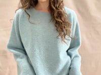 video of A woman wears a lightweight pointelle cashmere sweater jumper in pale blue turquoise with bronze silk skirt