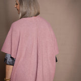 a woman wears a luxury throwover cashmere shawl cardigan in dusty pink over silk top and trousers in pewter by Irish Cashmere brand Madigan Cashmere