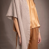 A woman wears a beige cashmere lace textured wrap throw over bronze silk clothing by Irish brand Madigan Cashmere