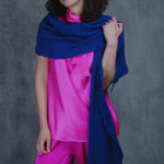 a woman wears a lace cashmere wrap shawl in indigo blue over her bright pink silk clothing
