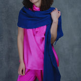 a woman wears a lace cashmere wrap shawl in indigo blue over her bright pink silk clothing