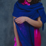 a woman wears a lace cashmere wrap shawl in indigo blue over her bright pink silk clothing