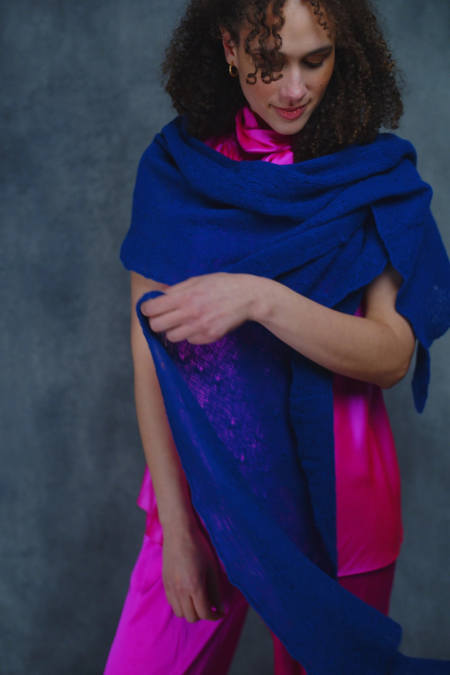 a woman wears a lace cashmere wrap shawl in indigo blue over her bright pink silk clothing