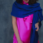 a woman wears a lace cashmere wrap shawl in indigo blue over her bright pink silk clothing